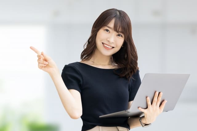 パソコンを持って指をさす女性